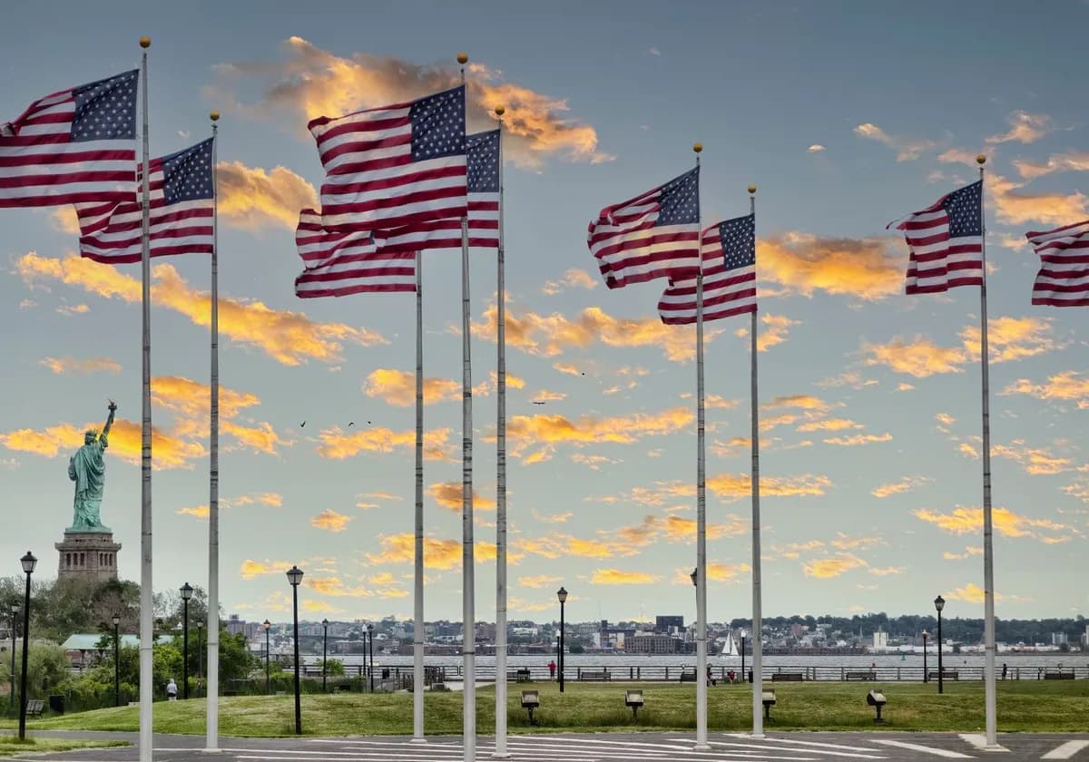 Waving American flags with the Statue of Liberty under a colorful sunset sky in Jersey City, NJ.