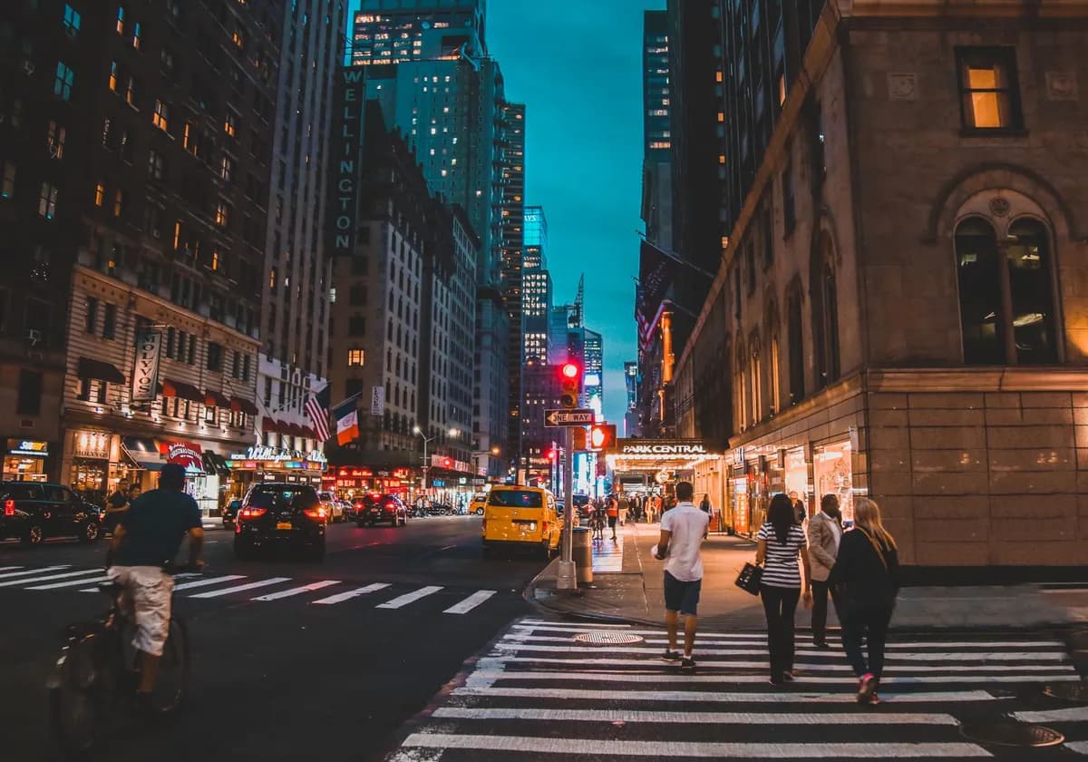 Busy streets of New York City illuminated at night with vibrant lights and bustling traffic.