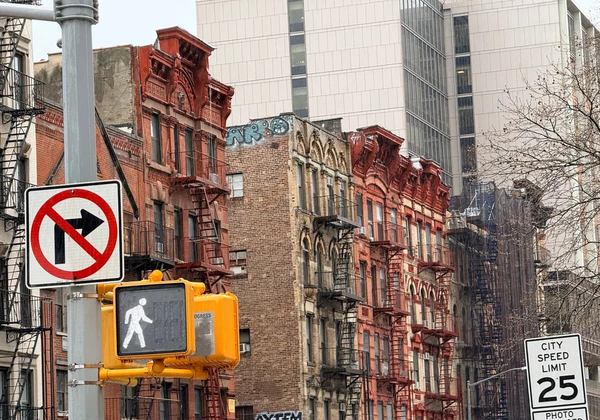 Historic New York City street with red brick brownstones and traffic signs.