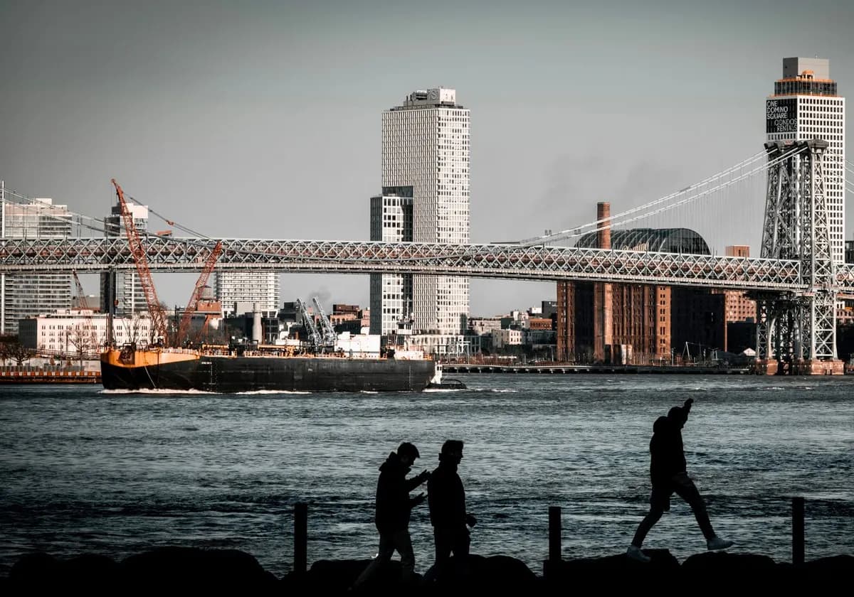 Silhouette of people walking by the Williamsburg Bridge and city skyline in New York City.