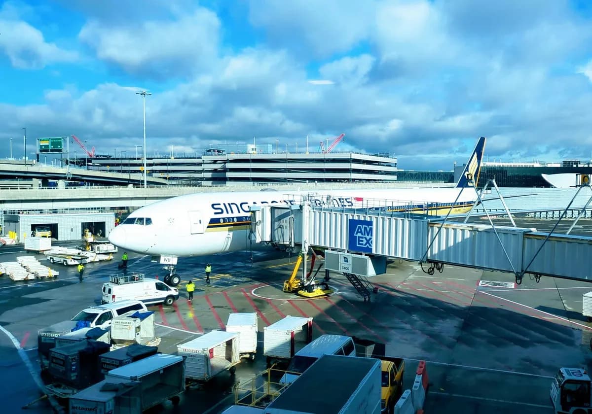 Singapore Airlines Boeing 777 at JFK Airport gate with jet bridge and ground support equipment.