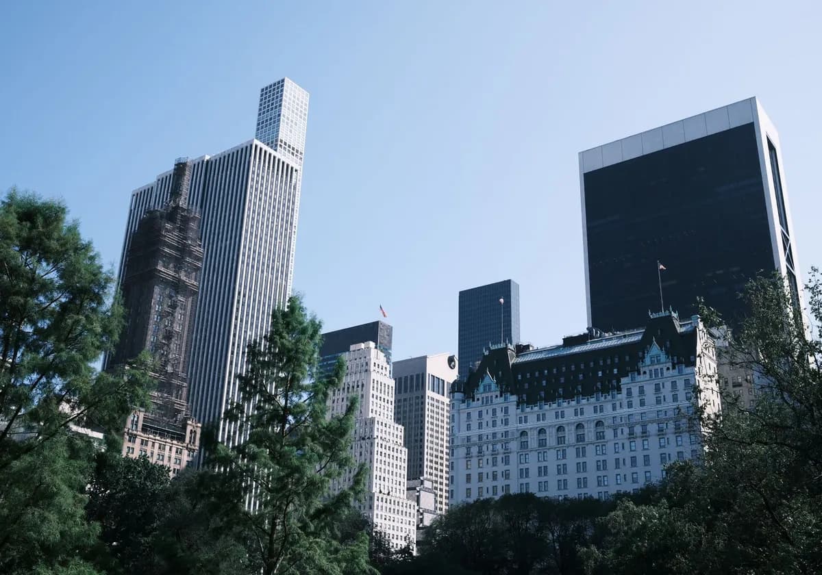 A view of New York City's skyline featuring the iconic Plaza Hotel and modern skyscrapers against a clear sky.