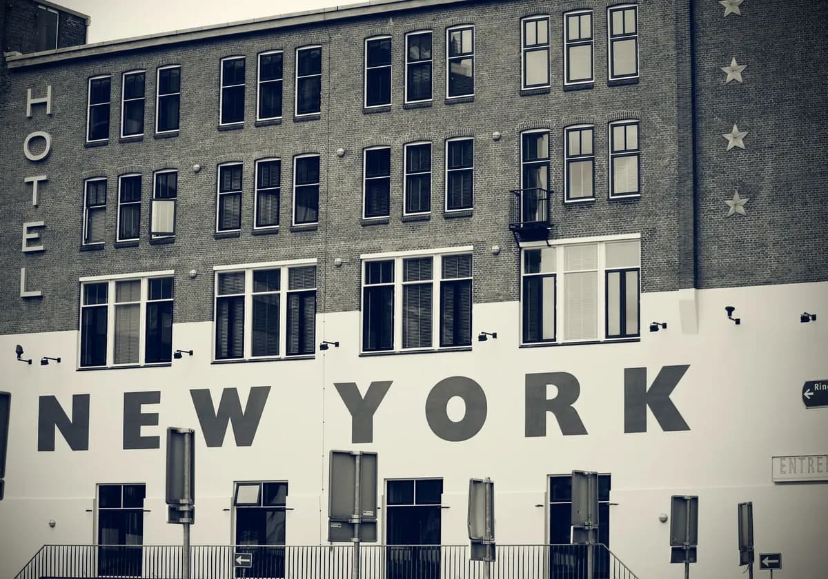 Black and white photo of a hotel facade with 'New York' signage, showcasing urban architecture.