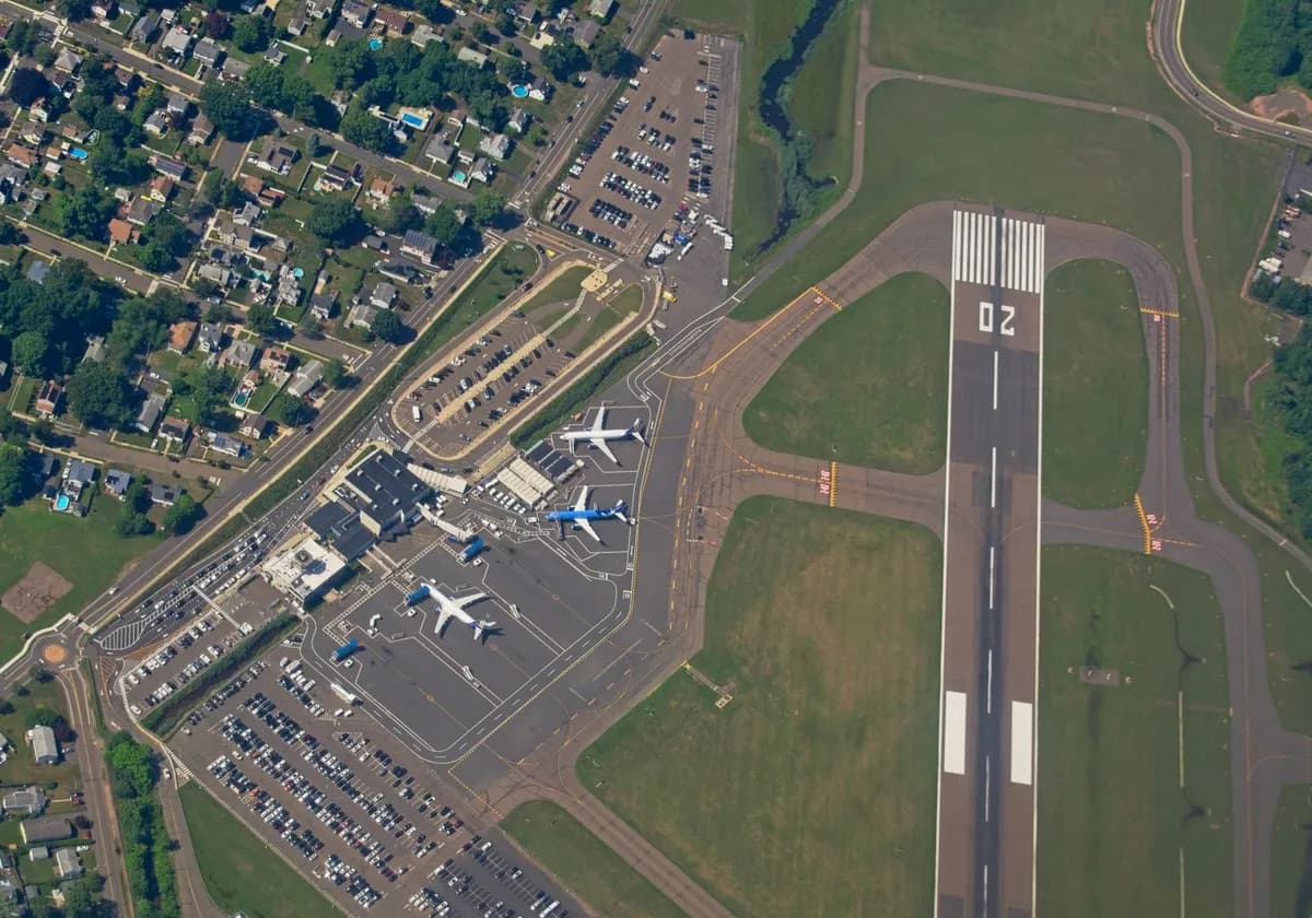 Aerial shot of an airport in New York, showcasing runways, planes, and nearby neighborhoods.