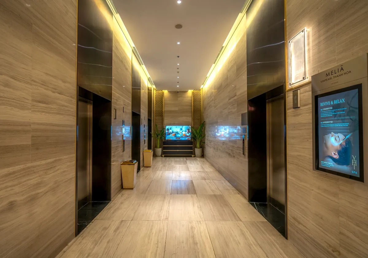 Elegant hotel corridor featuring marble floors and ambient lighting, exuding luxury.