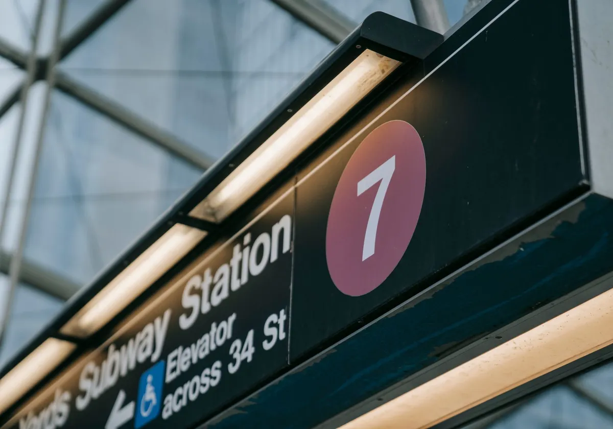 Close-up of a subway station sign with the number seven, located in New York City.