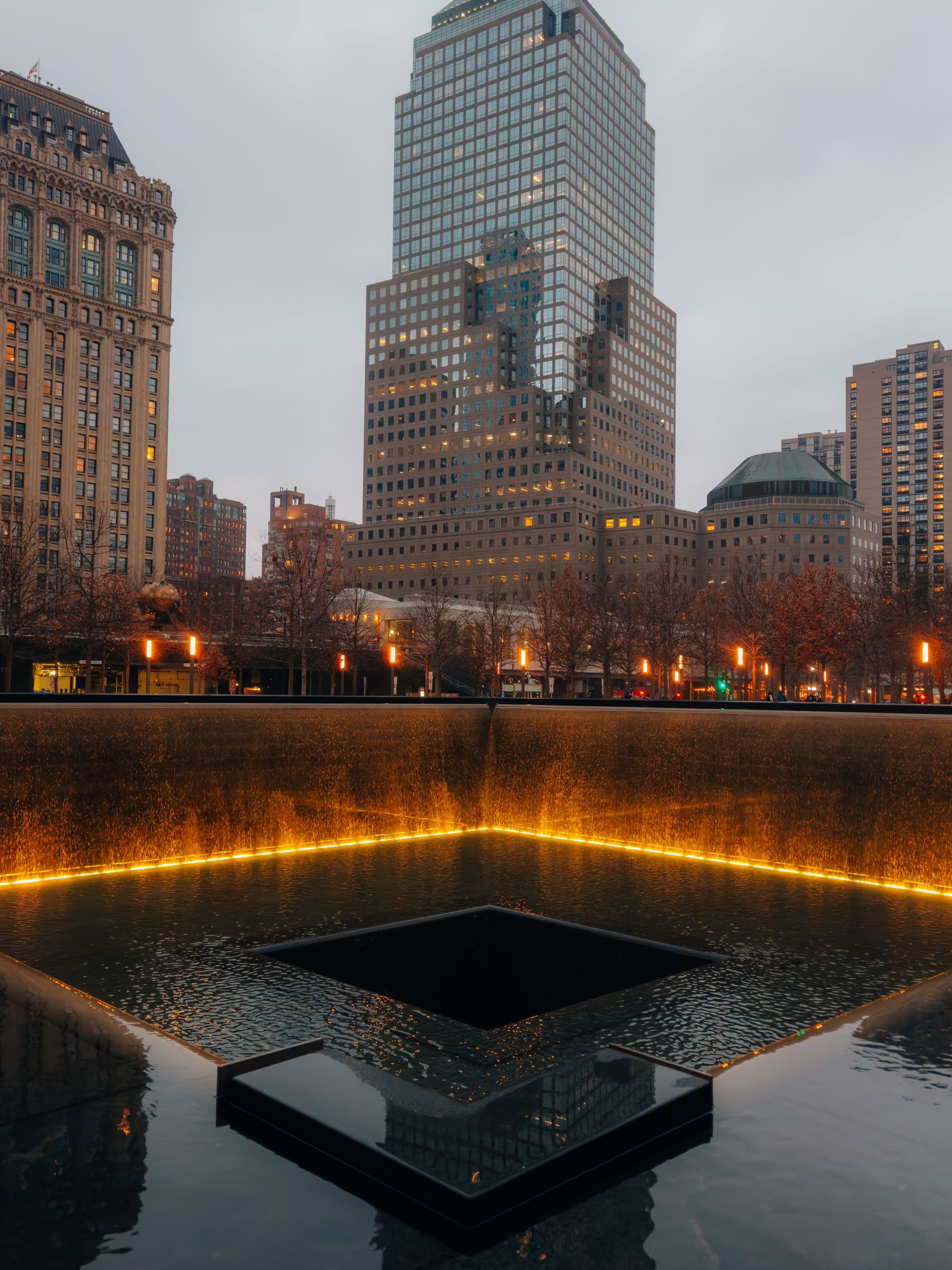 The 9/11 Memorial reflecting pool illuminated at dusk